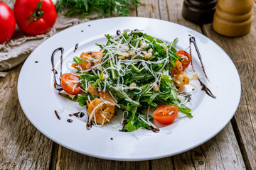 Arugula with shrimps on wooden table