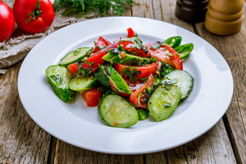 Vegetable salad with tomatoes and cucumbers on wooden table