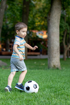 Little boy play soccer at outdoor.Boy running towards ball on a field