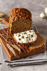 Loaf of pumpkin bread on wooden cutting board. Slice of bread with cream cheese.