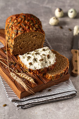 Loaf of pumpkin bread on wooden cutting board. Slice of bread with cream cheese.