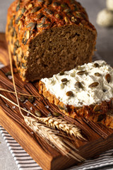 Loaf of pumpkin bread on wooden cutting board. Slice of bread with cream cheese.