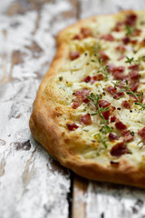 Alsatian tarte flambe with bacon and onions on a wooden background. Flammkuchen, Alsace thin pizza.