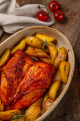 Roasted chicken and potato wedges on wooden table