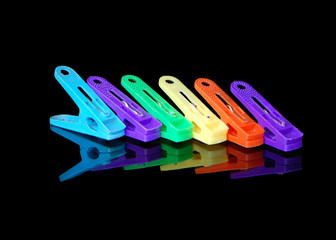 A colorful set of fun plastic clothes pegs on glass with a bright reflection