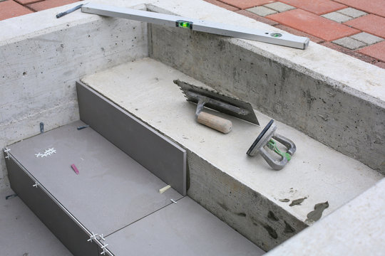 Tiler hands working on a new house entrance, local and professional handyman applying tiles to the steps.
