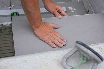 Tiler hands working on a new house entrance, local and professional handyman applying tiles to the steps.