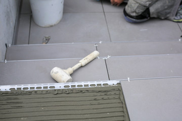Tiler hands working on a new house entrance, local and professional handyman applying tiles to the steps.