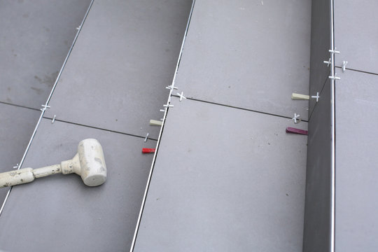 Tiler hands working on a new house entrance, local and professional handyman applying tiles to the steps.