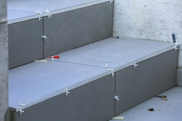 Tiler hands working on a new house entrance, local and professional handyman applying tiles to the steps.