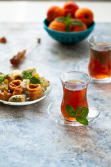 Different oriental sweets on glass plate and turkish tea cups. Baklava,halva,apricots.