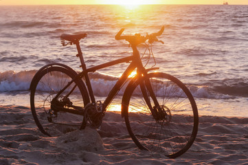 Fototapeta premium Bike and sunset by the sea. Black bike by the sea.