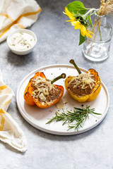Stuffed paprika with meat, quinoa and cheese on a plate. Baked stuffed yellow orange peppers.