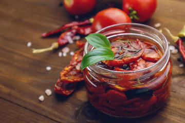 Glass jar with sun dried tomatoes on wooden table