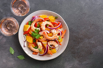 Ceviche with shrimps and orange, two glasses of pink sparkling wine, dark rustic background. Latin American food. Top view, copy space.