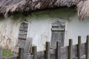 Fragment of old Ukrainian traditional house with straw roof, white clay walls and wooden windows. Historical authencity concept. Green tourism