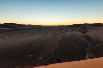 Fototapeta na wymiar The rising sun illuminating the mighty dunes of the sossusvlei, as seen from dune 45, in Nambia.