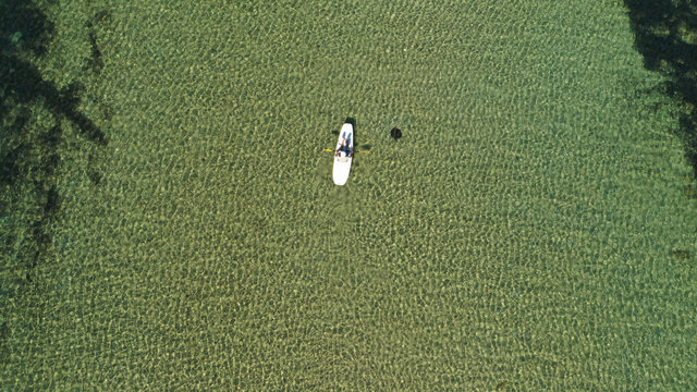 Aerial drone photo of young man practising canoe in tropical bay with calm sea