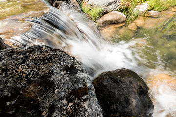 Naklejka na ściany i meble steam with water flowing on rocks near grass in park