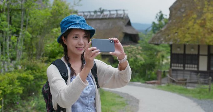 Woman use of mobile phone to take photo in Japanese wooden house