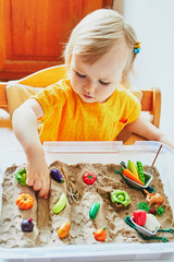 Adorable little girl playing with toy fruits and vegetables
