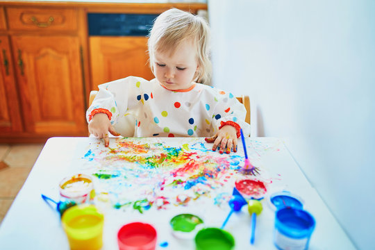 little girl painting with fingers at home