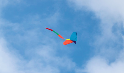 Angle view of a colorful kite flying, waving bow in a deep blue sky 