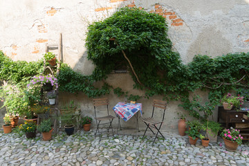 Patio mit Sitzgelegenheit und viel Grün an alter Hausfassade