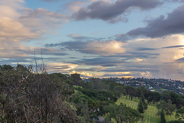 hillside view of cemetary with hillide homes, horizon, and panaramic cloudy sky