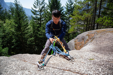 Rock Climber is Rappeling down a steep cliff during a sunny summer day. Taken in Squamish, British...