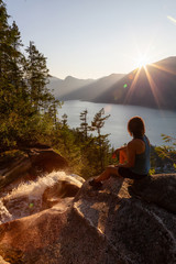 Adventurous Girl is sitting on top of a Beautiful Waterfall, Shannon Falls, and watching the sunset. Taken near Squamish, North of Vancouver, British Columbia, Canada.