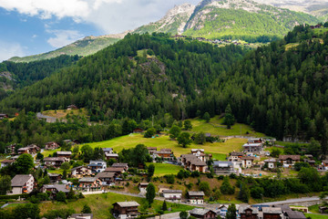 Fototapeta na wymiar Awesome alpine highlands. Breathtaking view of swiss village and mountains in the background. View from panoramic train to Zermatt, Switzerland