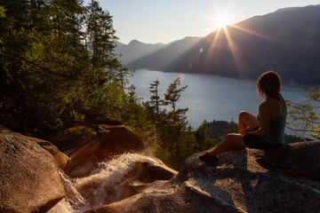 Adventurous Girl is sitting on top of a Beautiful Waterfall, Shannon Falls, and watching the...