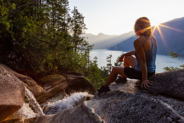 Adventurous Girl is sitting on top of a Beautiful Waterfall, Shannon Falls, and watching the...