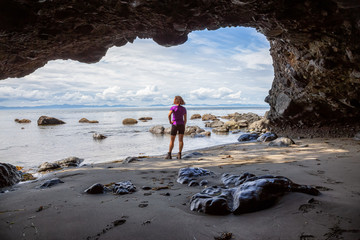 Adventurous girl hiking in a cave on Juan de Fuca Trail to Mystic Beach on the Pacific Ocean Coast...