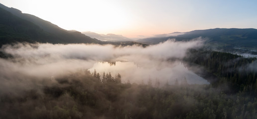 Obraz na płótnie Canvas Aerial Panoramic View of Fairy Lake covered in clouds during a vibrant summer sunrise. Taken near Port Renfrew, Vancouver Island, British Columbia, Canada.