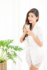 Portrait of a cute woman with brunet hair wearing white dress isolated over white background , drinking milk cocktail from a glass.