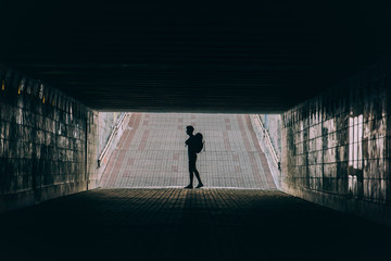 side view of young adult man with backpack in tunnel