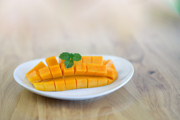 Beautifully peeled mango in white plate on wooden table.