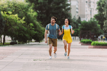 Fototapeta premium handsome man and asian woman running and looking away