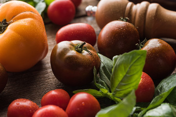 close up view of tomatoes with spinach near salt mill on wooden surface
