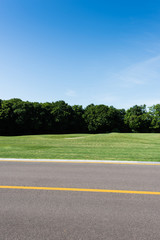 selective focus of yellow line on road near green park in summertime