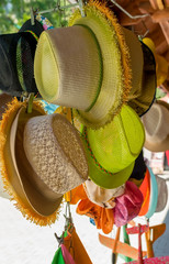 the kind of different straw tourist women's sun hats that hang and are sold in the market in the...