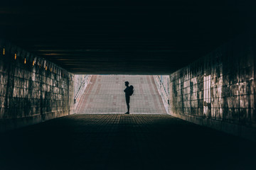 Silhouette of young man with backpack in tunnel