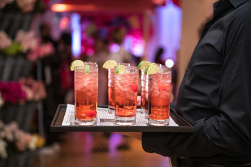 Refreshing alcohol red cocktails with ice and lemon on waiter plate on evening event party