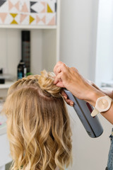 Fototapeta premium Hairtician builds upper bun. Hairstyle on bob. Hairdressing services. Creating evening hairstyles fashionable stylish women's hairstyles. Process of hair styling. Courses in hairdressing. Beauty salon