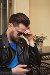 Side view fashion portrait of thinking stylish young handsome bearded hipster man in sunglasses....