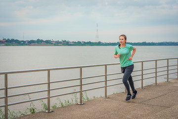 Woman running on the street with a view of the river in the morning.