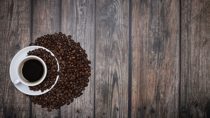 cup of coffee and beans on brown wooden table with text copy space