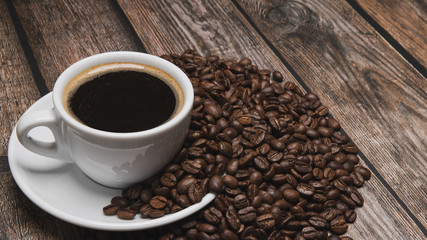 cup of coffee and beans on brown wooden table with text copy space